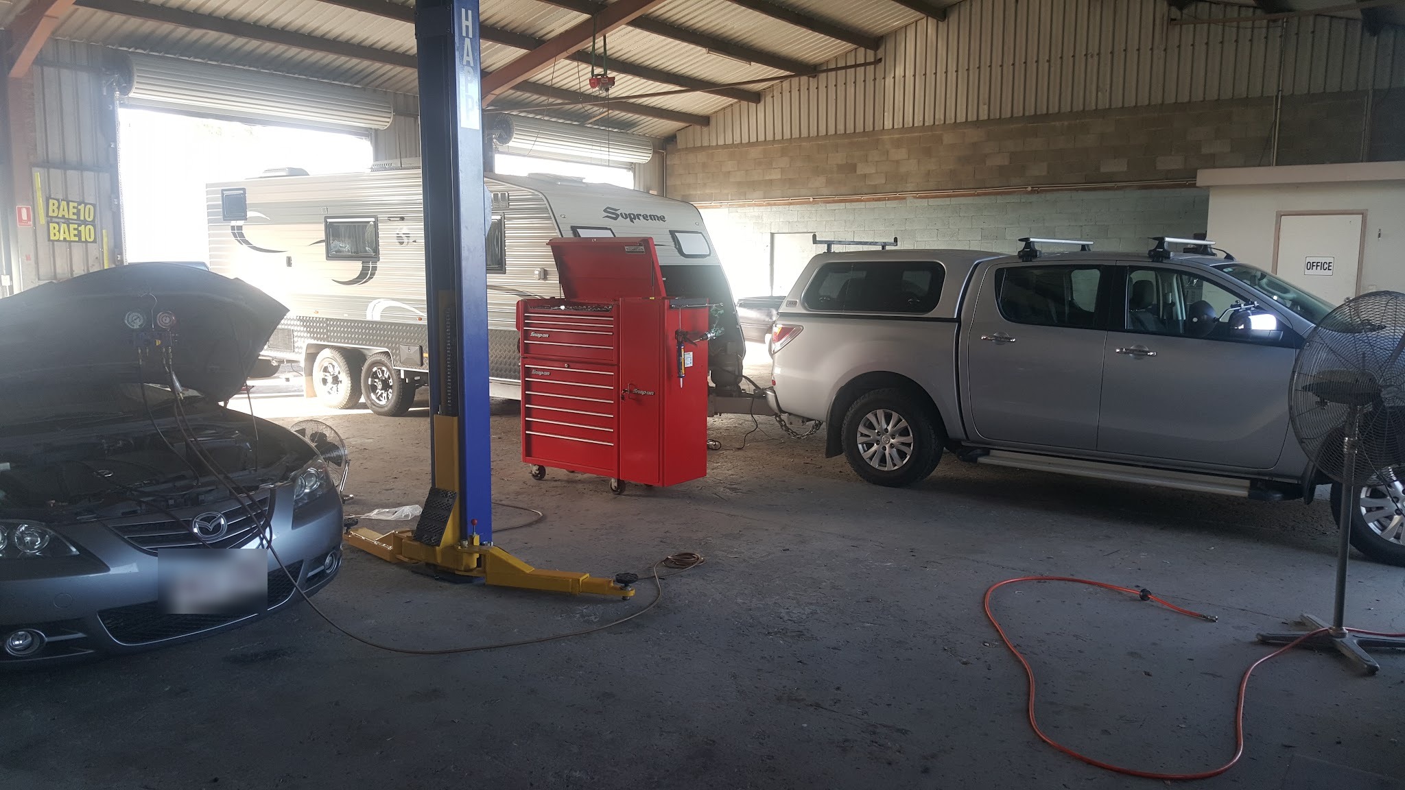 Air conditioning gauges connected to a car with the bonnet up in the workshop