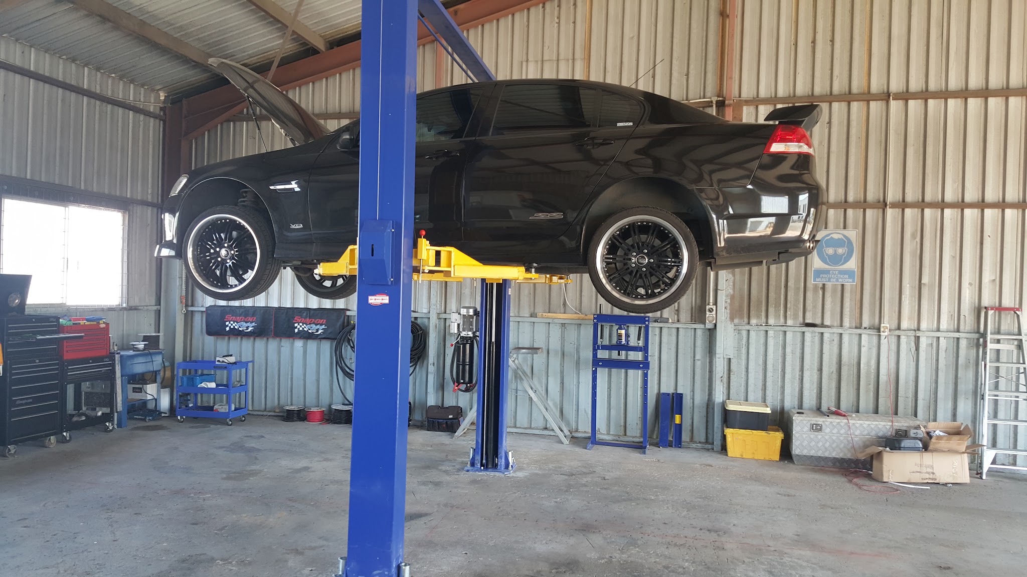 A Holden Commodore raised on the two post hoist in the workshop